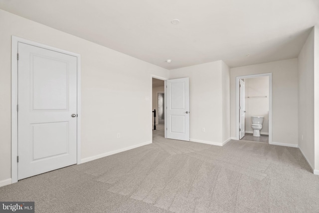 unfurnished bedroom featuring light carpet and ensuite bath