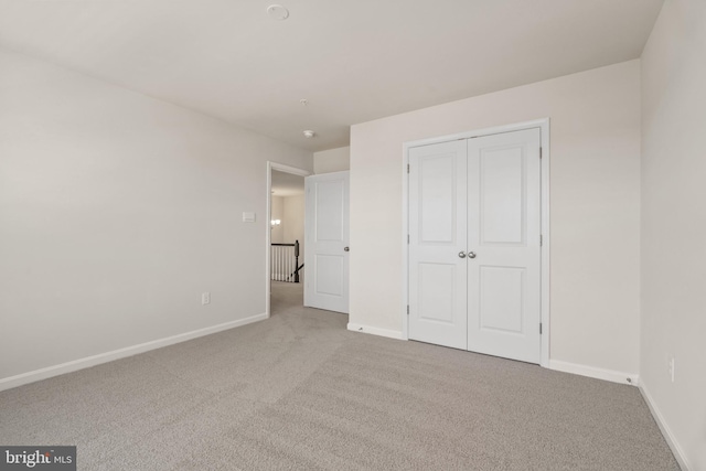 unfurnished bedroom with light colored carpet and a closet