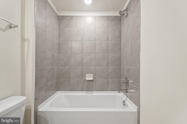 bathroom featuring tiled shower / bath combo and toilet