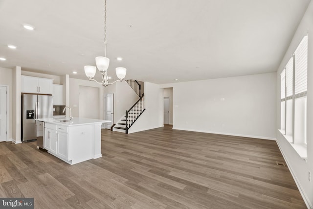 kitchen featuring sink, a kitchen island with sink, white cabinetry, stainless steel appliances, and decorative light fixtures