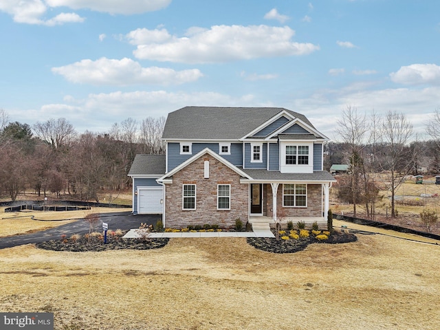 view of front of property featuring a garage, a front yard, and covered porch