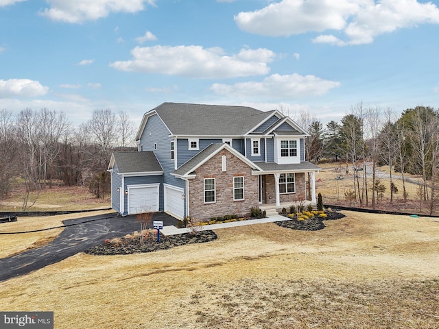 view of front of property featuring a garage, covered porch, and a front yard