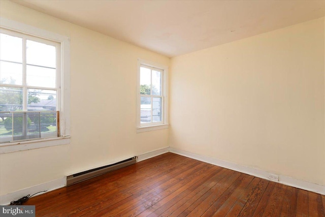 unfurnished room with hardwood / wood-style flooring and a baseboard heating unit