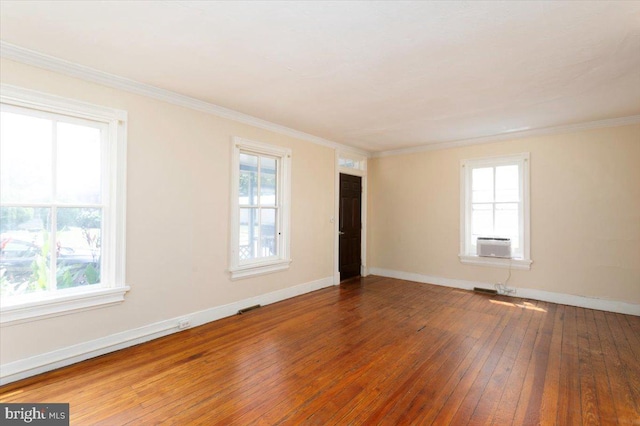 empty room featuring hardwood / wood-style flooring, ornamental molding, and a wealth of natural light