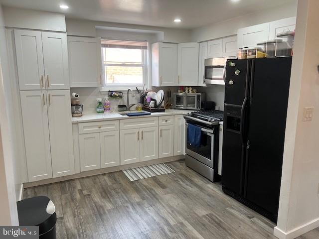 kitchen featuring appliances with stainless steel finishes, sink, white cabinets, and light hardwood / wood-style flooring