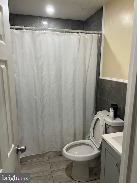 bathroom with vanity, toilet, tile patterned flooring, and tile walls