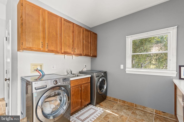 laundry area with cabinets, washing machine and dryer, and sink