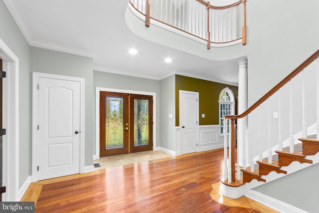 entrance foyer featuring crown molding, light hardwood / wood-style flooring, decorative columns, and french doors