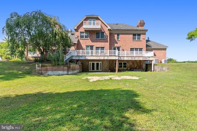 back of house featuring a balcony, a yard, and french doors