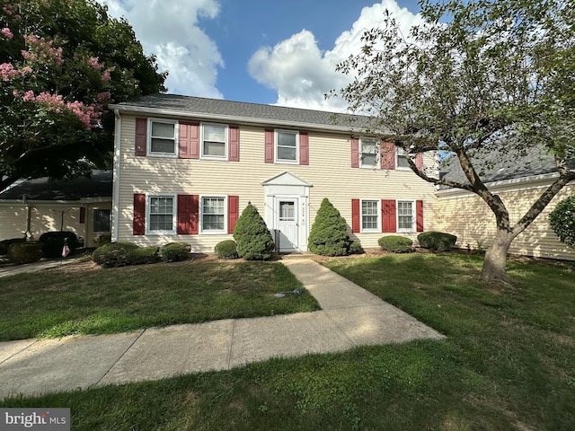 colonial-style house featuring a front lawn