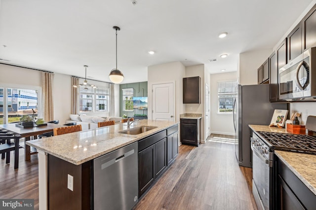 kitchen with decorative light fixtures, sink, a kitchen island with sink, stainless steel appliances, and dark brown cabinets