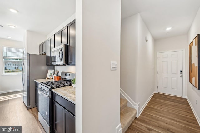 kitchen featuring stainless steel appliances, light stone counters, and light hardwood / wood-style flooring