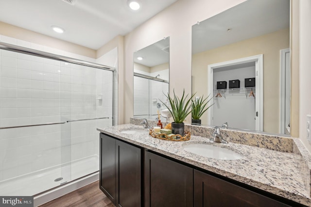 bathroom with wood-type flooring, vanity, and a shower with shower door