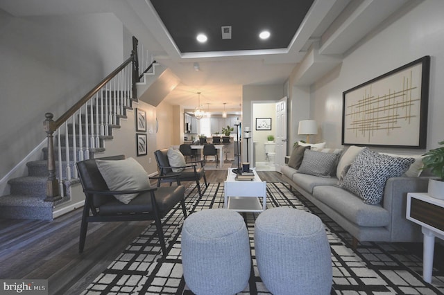 living room featuring wood-type flooring, a chandelier, and a tray ceiling