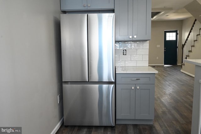 kitchen featuring dark hardwood / wood-style flooring, backsplash, stainless steel fridge, and gray cabinets