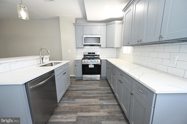 kitchen with sink, dark wood-type flooring, gray cabinets, stainless steel appliances, and decorative light fixtures