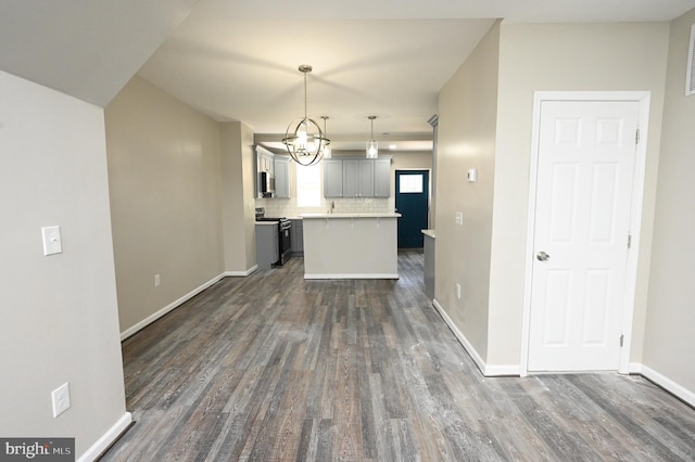 kitchen with dark hardwood / wood-style floors, decorative light fixtures, gray cabinetry, backsplash, and stainless steel gas range oven