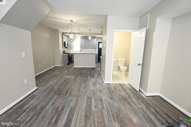 kitchen featuring a kitchen island, backsplash, hanging light fixtures, stainless steel appliances, and dark wood-type flooring