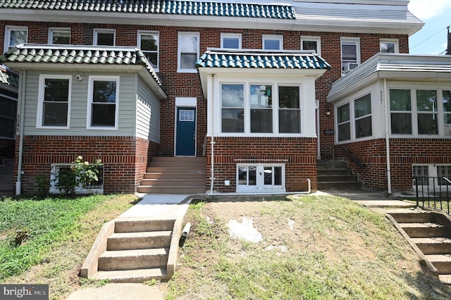 back of property featuring brick siding and stairs