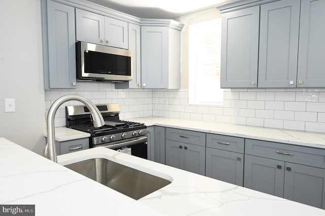 kitchen featuring light stone counters, stainless steel appliances, and decorative backsplash