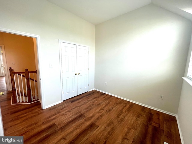 unfurnished bedroom with vaulted ceiling, dark hardwood / wood-style floors, and a closet