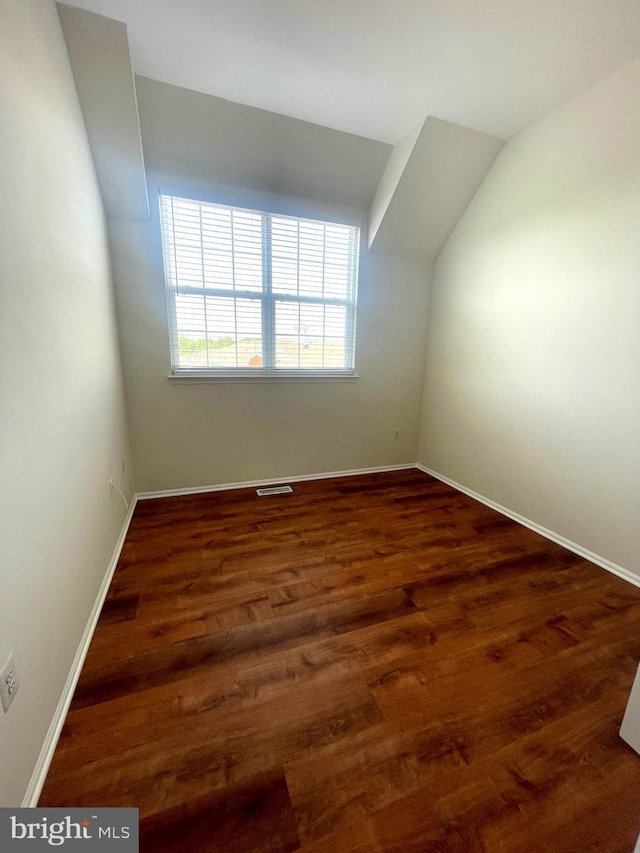 bonus room with dark hardwood / wood-style floors and vaulted ceiling