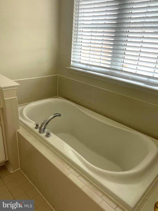 bathroom featuring tiled tub, vanity, and tile patterned floors