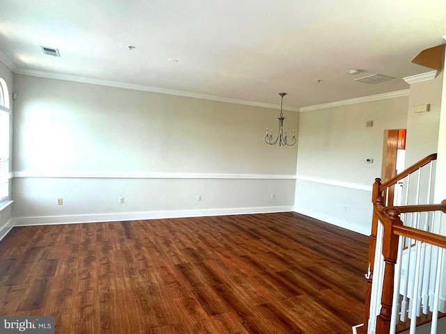 empty room featuring crown molding, dark wood-type flooring, and a notable chandelier