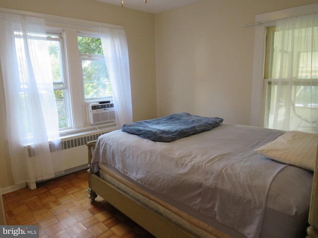 bedroom with light parquet floors and radiator heating unit