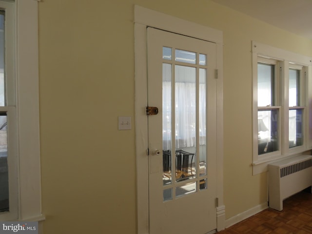 entryway with radiator heating unit and dark parquet floors