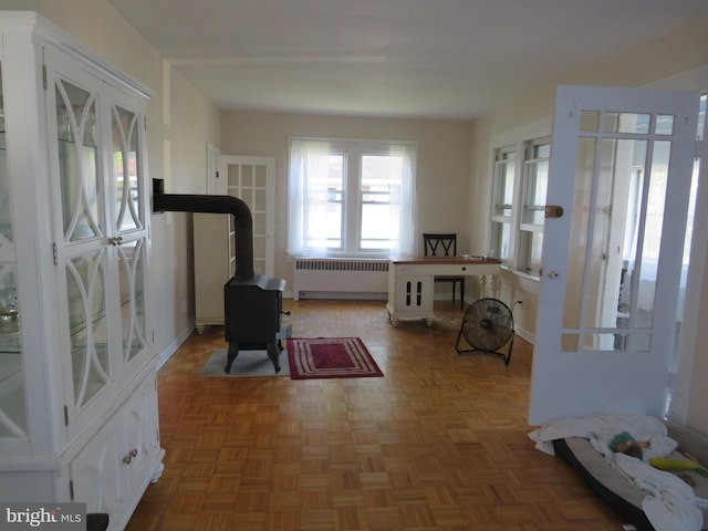 interior space featuring dark parquet flooring, radiator, and a wood stove