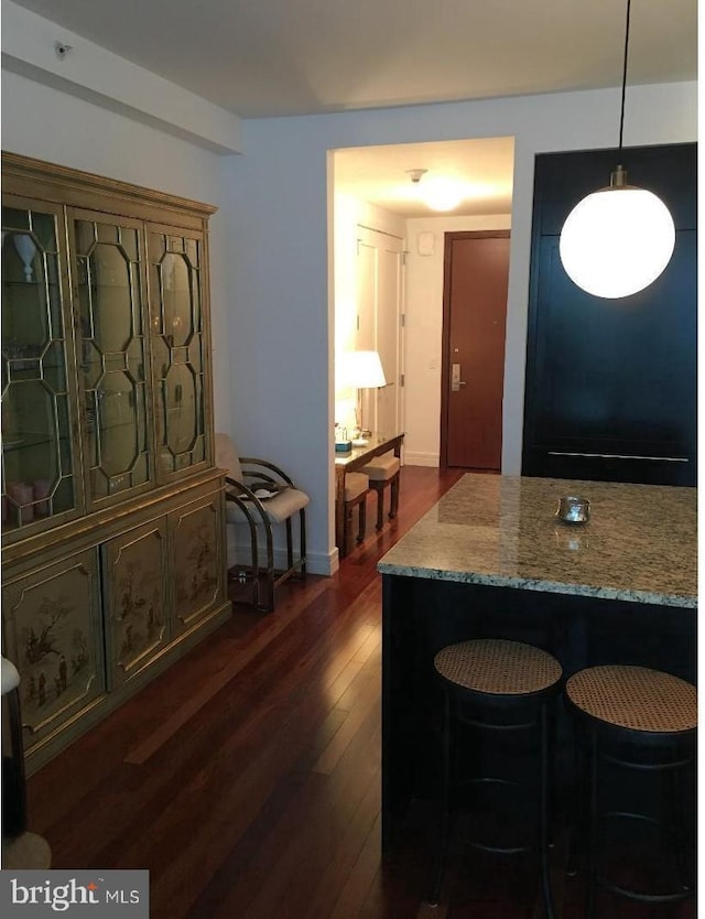 kitchen featuring light stone counters, dark hardwood / wood-style flooring, and decorative light fixtures