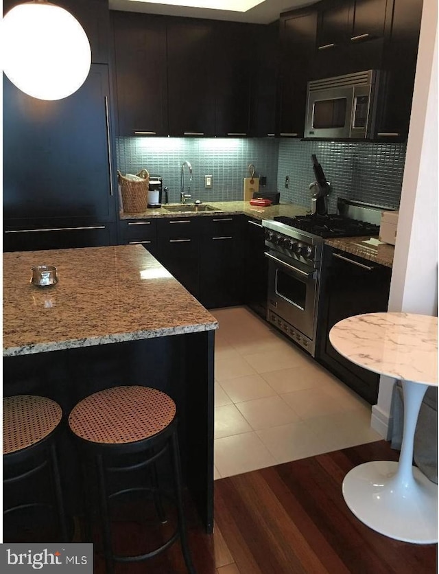 kitchen with appliances with stainless steel finishes, sink, backsplash, a kitchen breakfast bar, and a center island