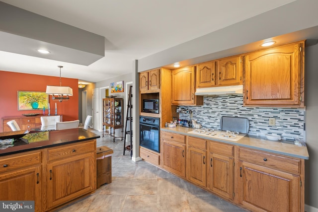 kitchen featuring hanging light fixtures, backsplash, and black appliances