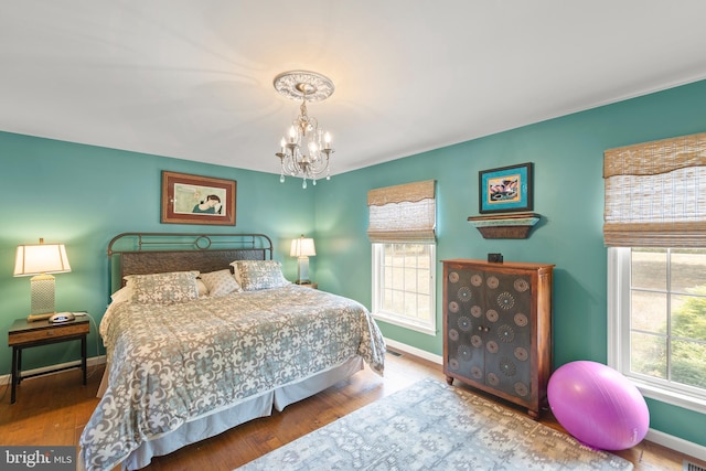 bedroom with multiple windows, hardwood / wood-style floors, and a notable chandelier