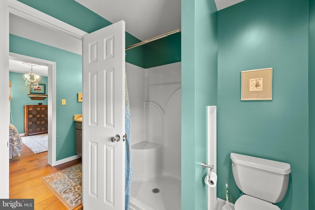 bathroom with walk in shower, wood-type flooring, toilet, and an inviting chandelier