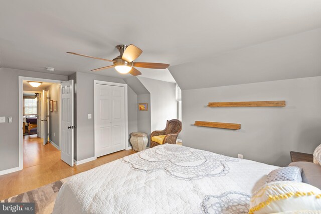 bedroom with vaulted ceiling, ceiling fan, light wood-type flooring, and a closet