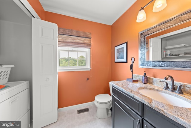 bathroom featuring vanity, washer / dryer, and toilet