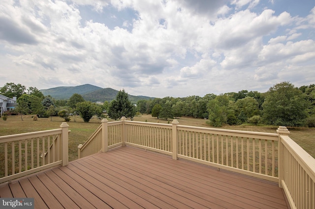 wooden deck featuring a mountain view and a lawn