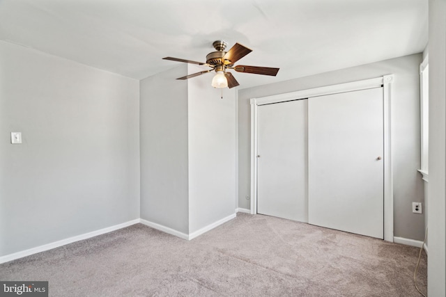 unfurnished bedroom with ceiling fan, a closet, and light carpet