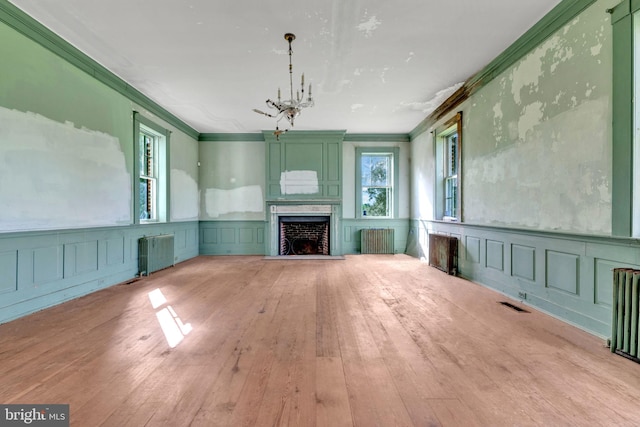 unfurnished living room with hardwood / wood-style flooring, ornamental molding, and radiator heating unit