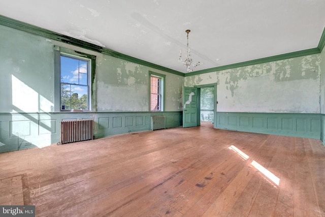 interior space with a notable chandelier, radiator heating unit, light hardwood / wood-style floors, and a healthy amount of sunlight