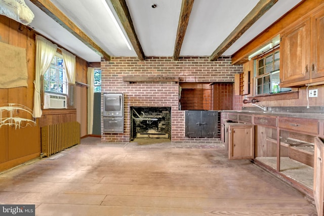 kitchen featuring radiator heating unit, light hardwood / wood-style flooring, cooling unit, and beam ceiling