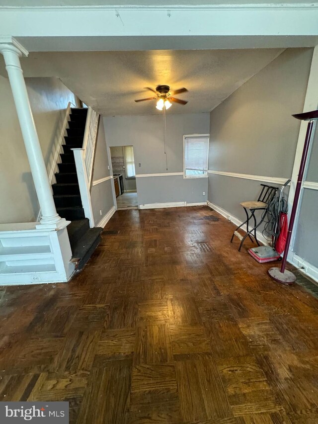 foyer entrance with decorative columns, ceiling fan, and dark parquet flooring