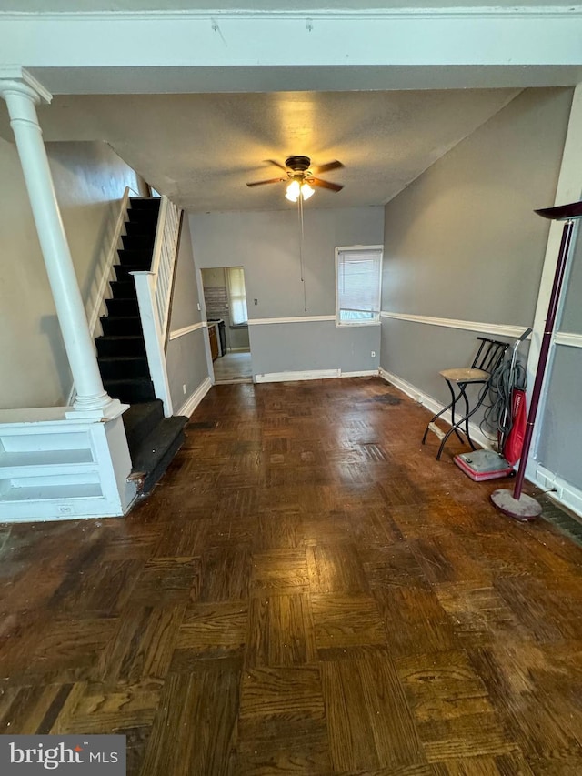 unfurnished living room featuring dark parquet floors, decorative columns, and ceiling fan