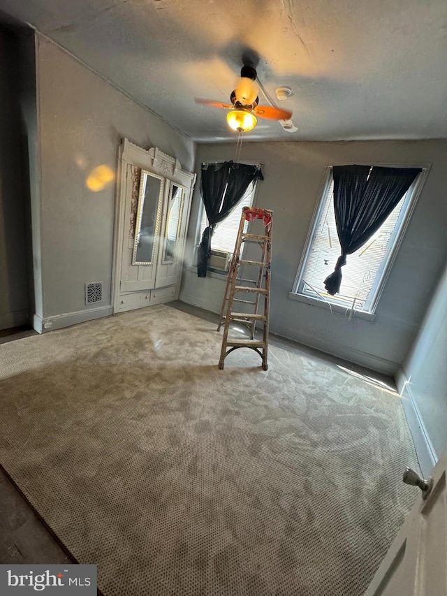 interior space with carpet floors, cooling unit, and ceiling fan