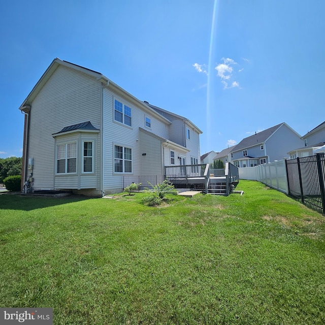 back of property with a wooden deck and a yard