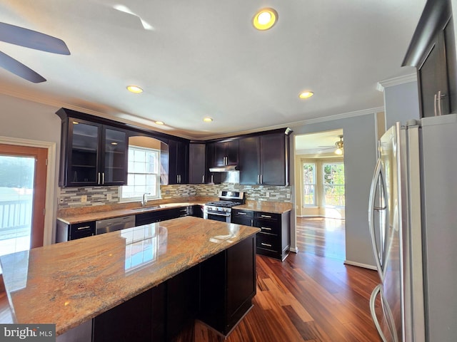 kitchen with sink, tasteful backsplash, ornamental molding, appliances with stainless steel finishes, and light stone countertops