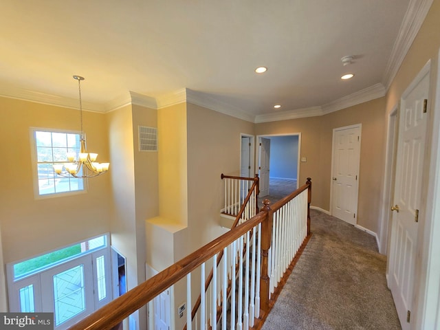 hallway featuring dark colored carpet, ornamental molding, and a notable chandelier