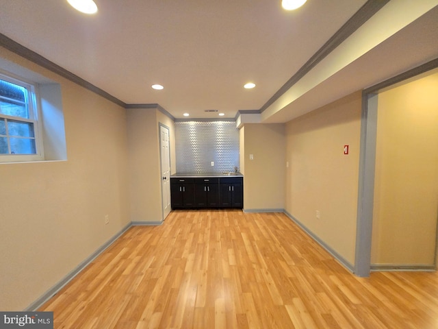 basement featuring crown molding and light hardwood / wood-style flooring